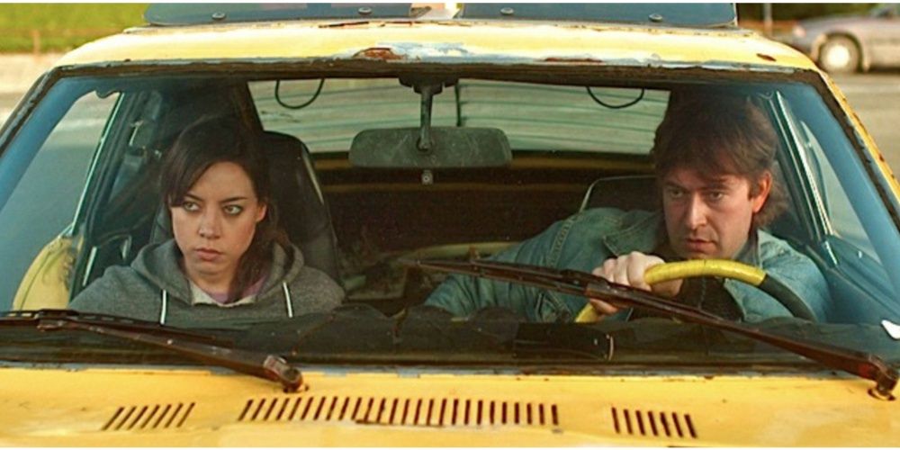 Aubrey Plaza and Mark Duplass sit in a yellow car