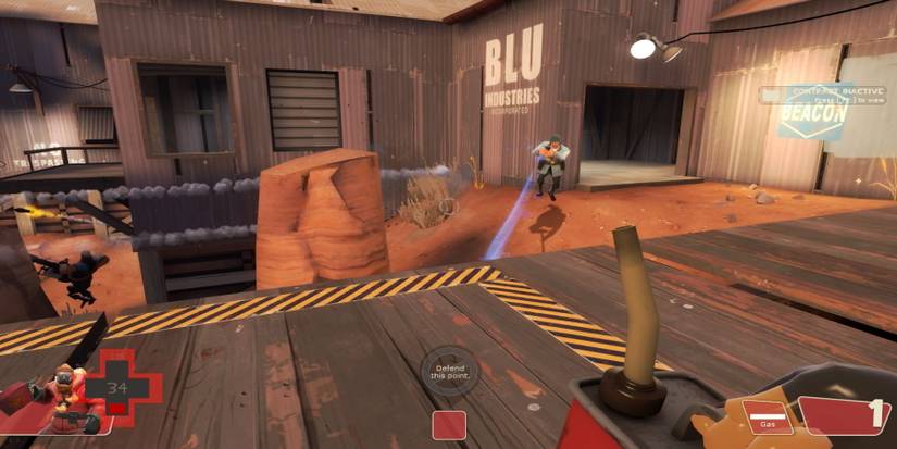 A Pyro holding a can of petrol on a capture point while a Soldier, currently being healed, moves outside a metal building