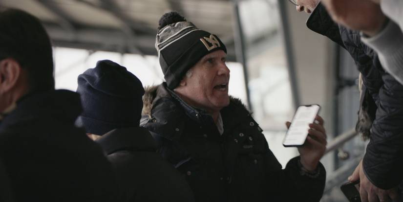 Will Ferrell holding phone in Wrexham stadium stands