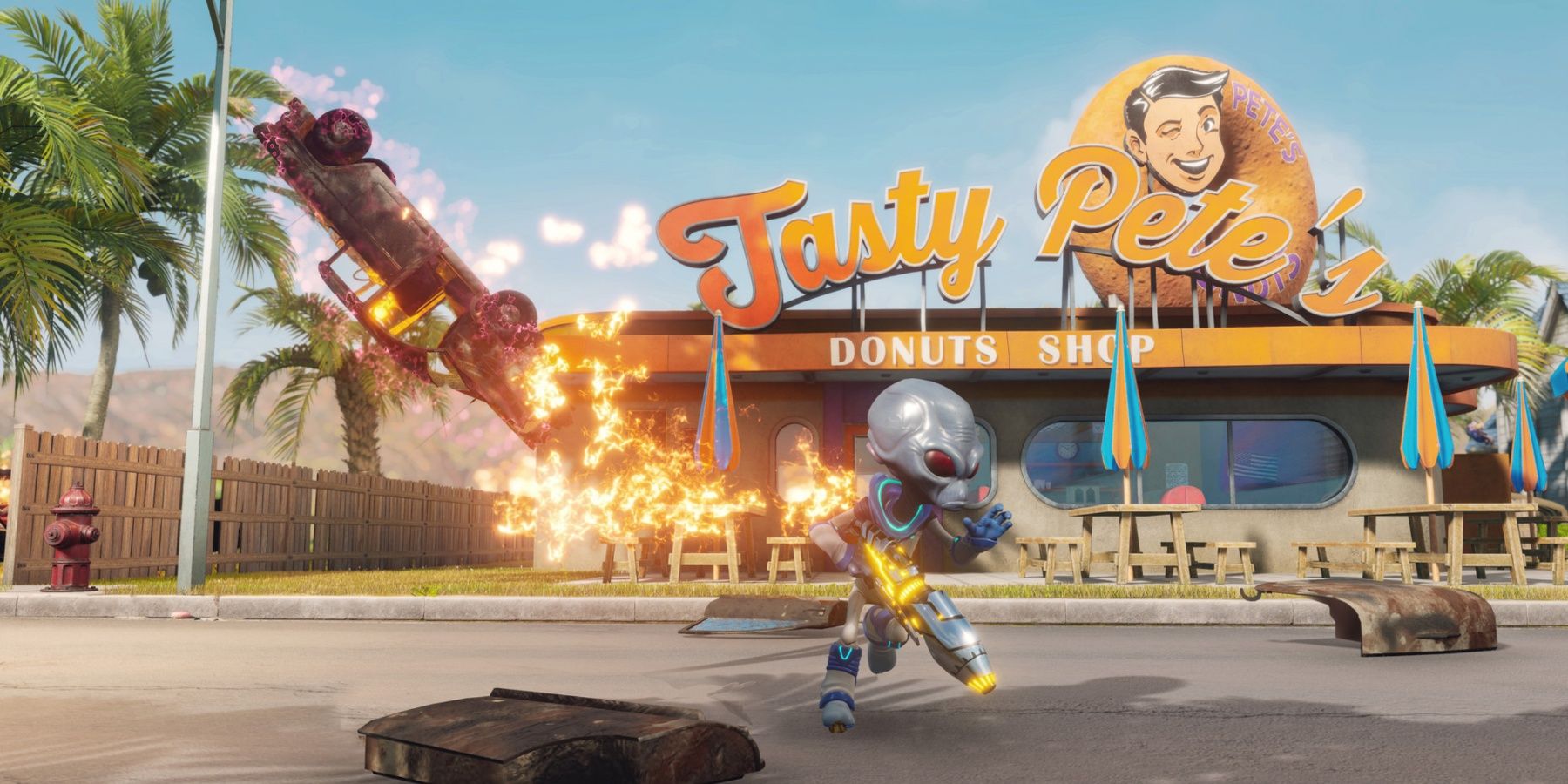 An alien standing in front of a 50s style donut shop as a pick up flies through the air on fire