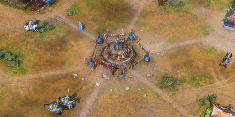 Some units from the Mongol empire making their way around a building in Age Of Empires 4