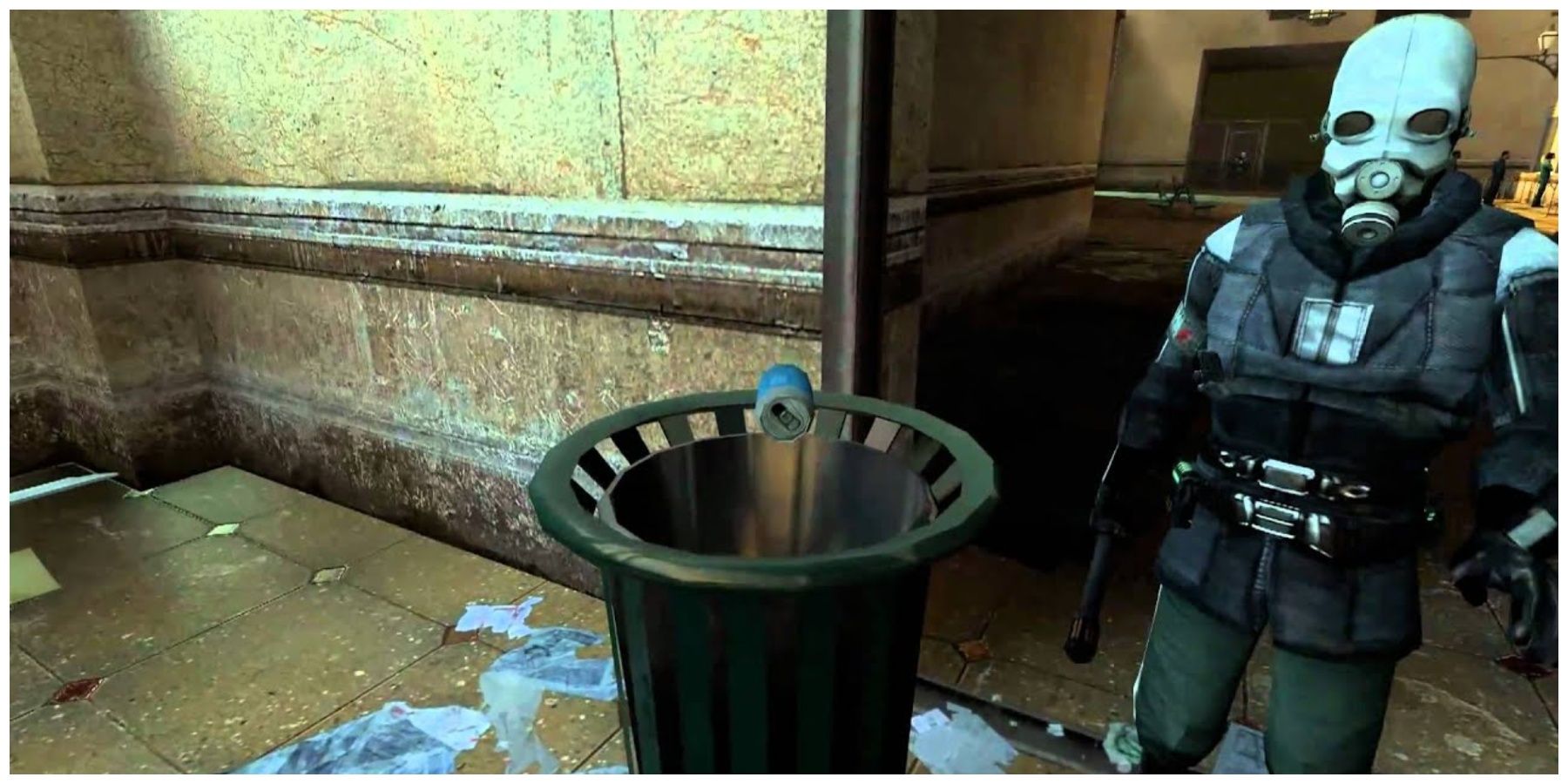 A bin with a can floating above it and a guard with a full face helmet standing next to it