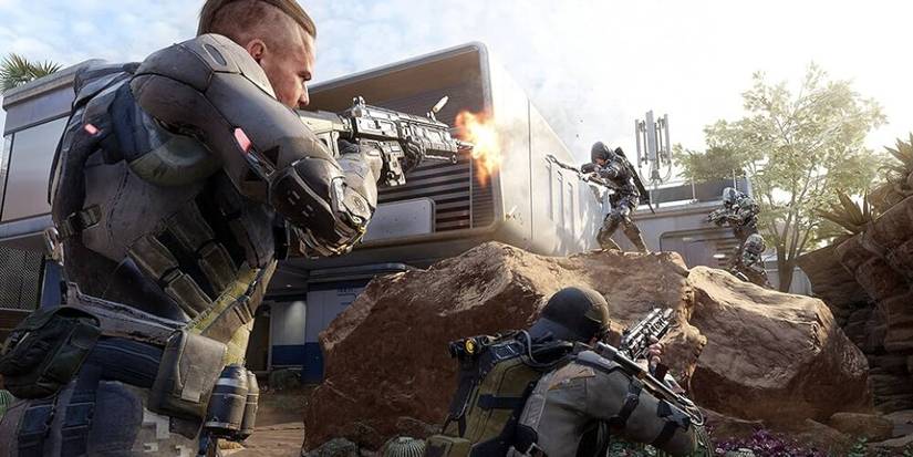 Two soldiers shooting two enemies standing on a boulder