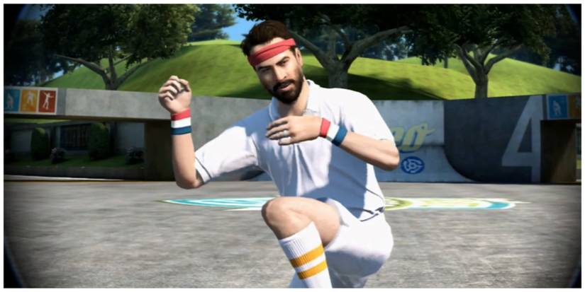 A man in a white polo and shorts with a red headband poses in a skate park