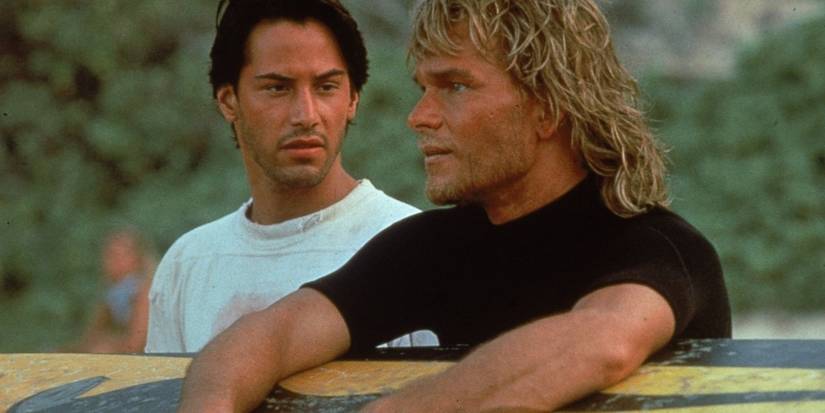 Keanu Reeves as Johnny Utah and Patrick Swayze as Bodhi with a surfboard in Point Break
