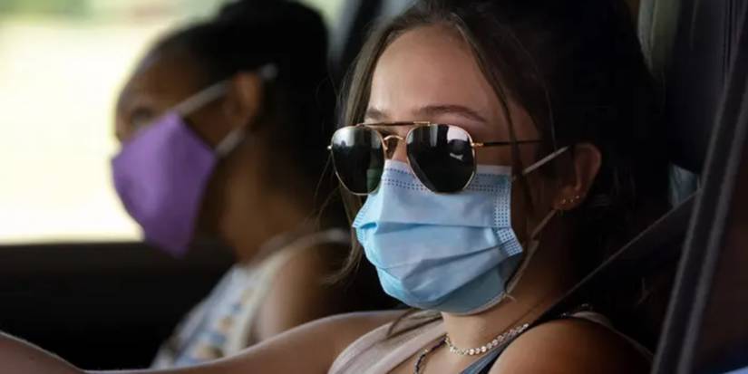 Beth Million as Miri and Gideon Adlon as Parker sitting in a car wearing masks in Sick