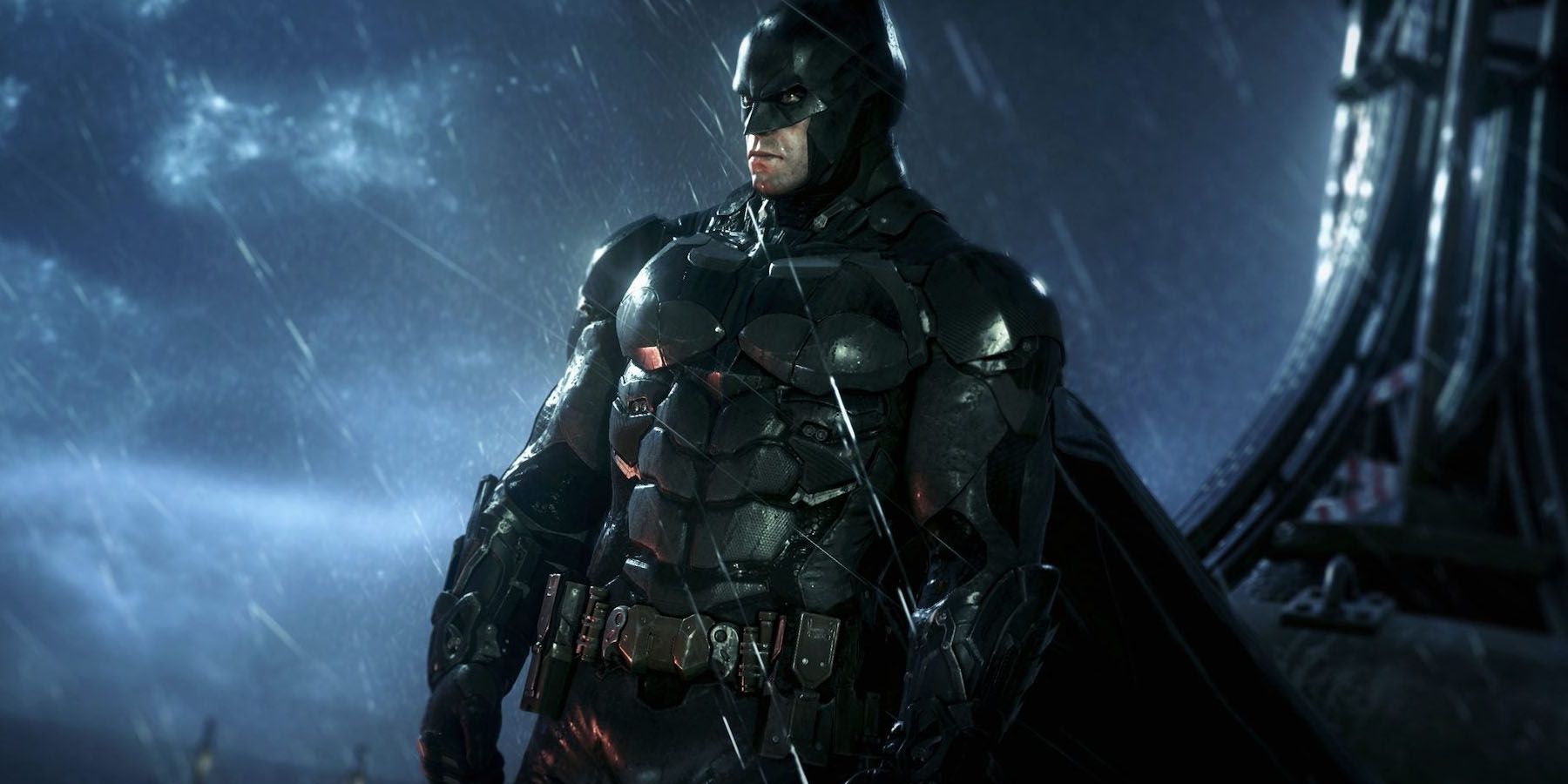 Uno screenshot di Batman che domina Gotham da un tetto piovoso con le orecchie da pipistrello ritagliate in Batman: Arkham Knight.