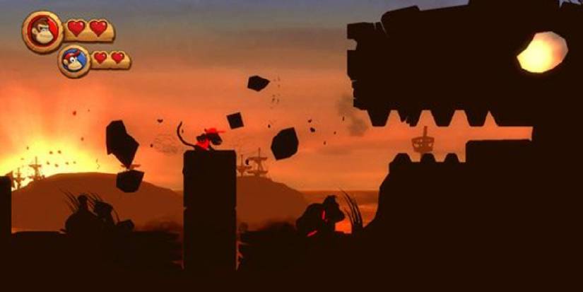 Diddy Kong and Donkey Kong facing the head of a dragon statue with glowing eyes against a sunset. All silhouetted. Image source: rawg.io