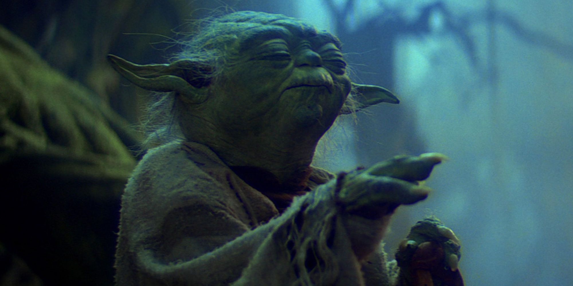 Yoda with his hand raised and eyes closed as he lifts Luke's X-Wing out of the swamp