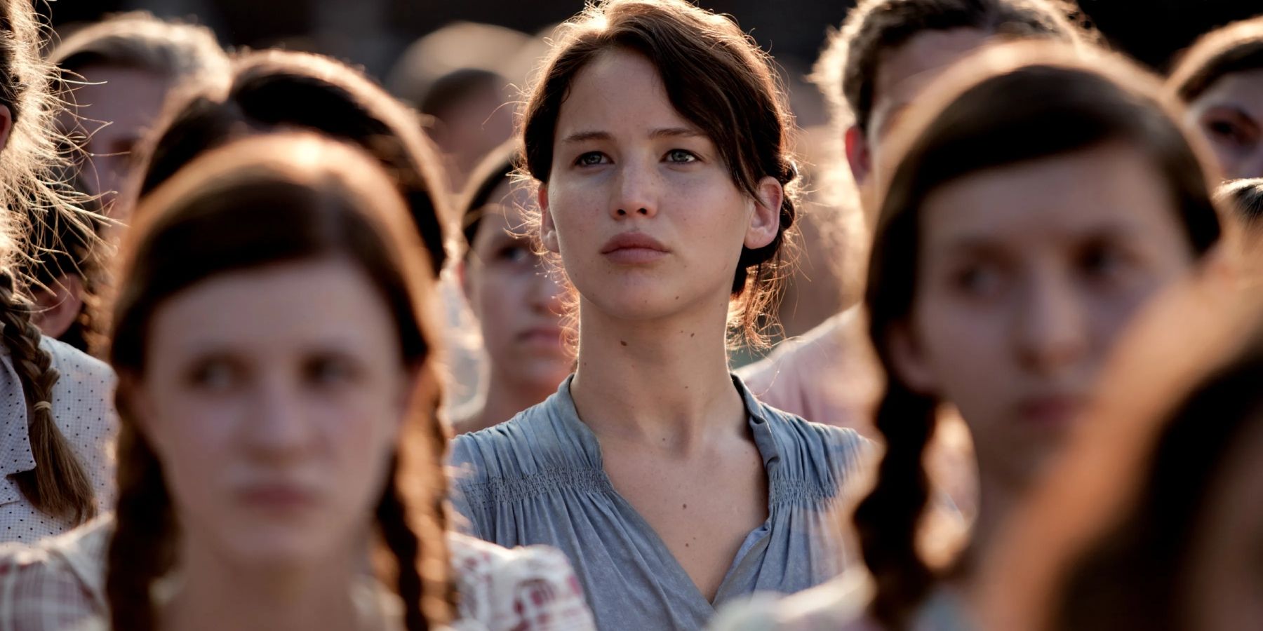 Katniss Everdeen (Jennifer Lawrence) standing with other District 12 residents in The Hunger Games