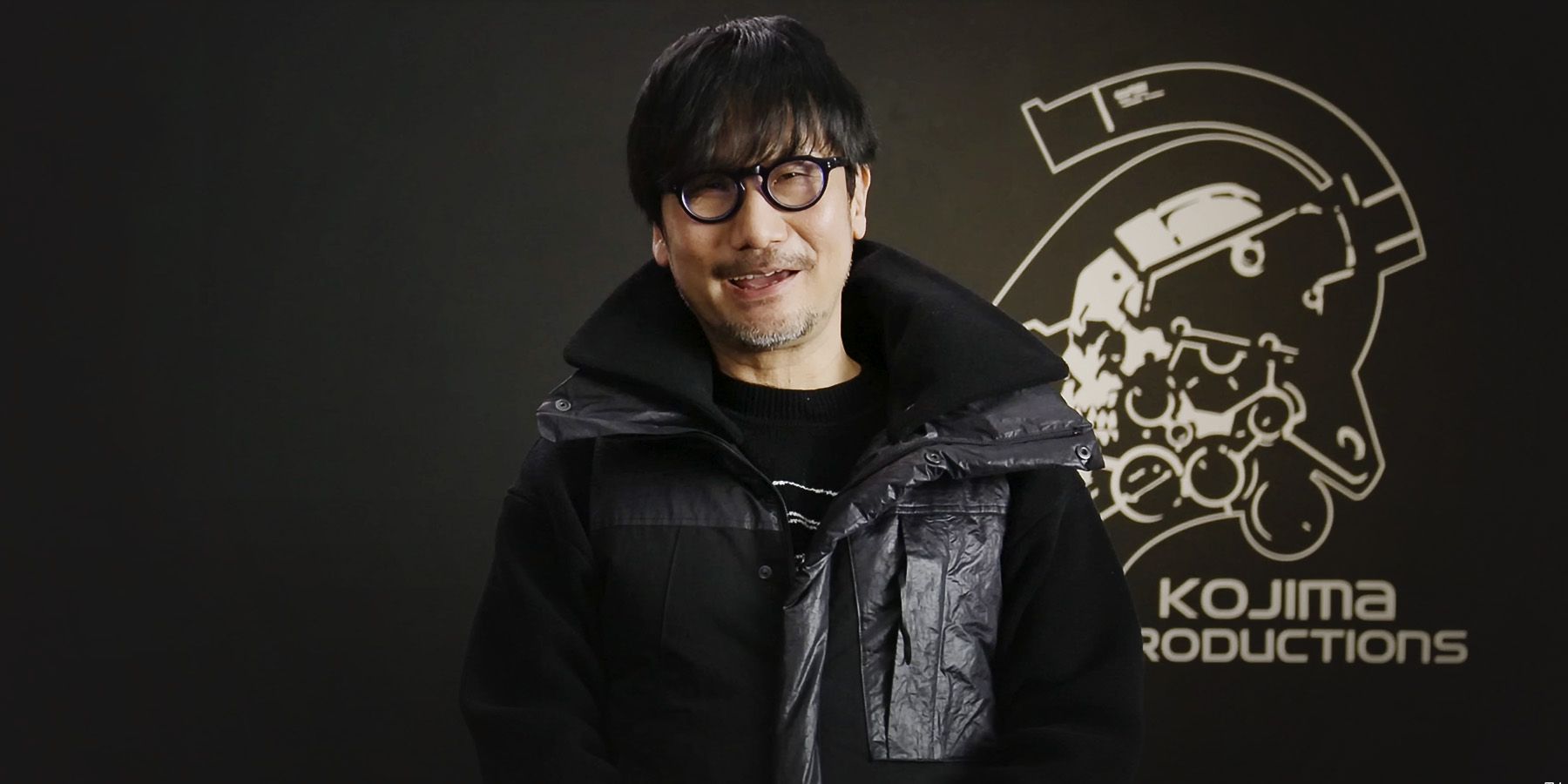 Hideo Kojima laughing next to Kojima Productions logo in PHYSINT announcement video