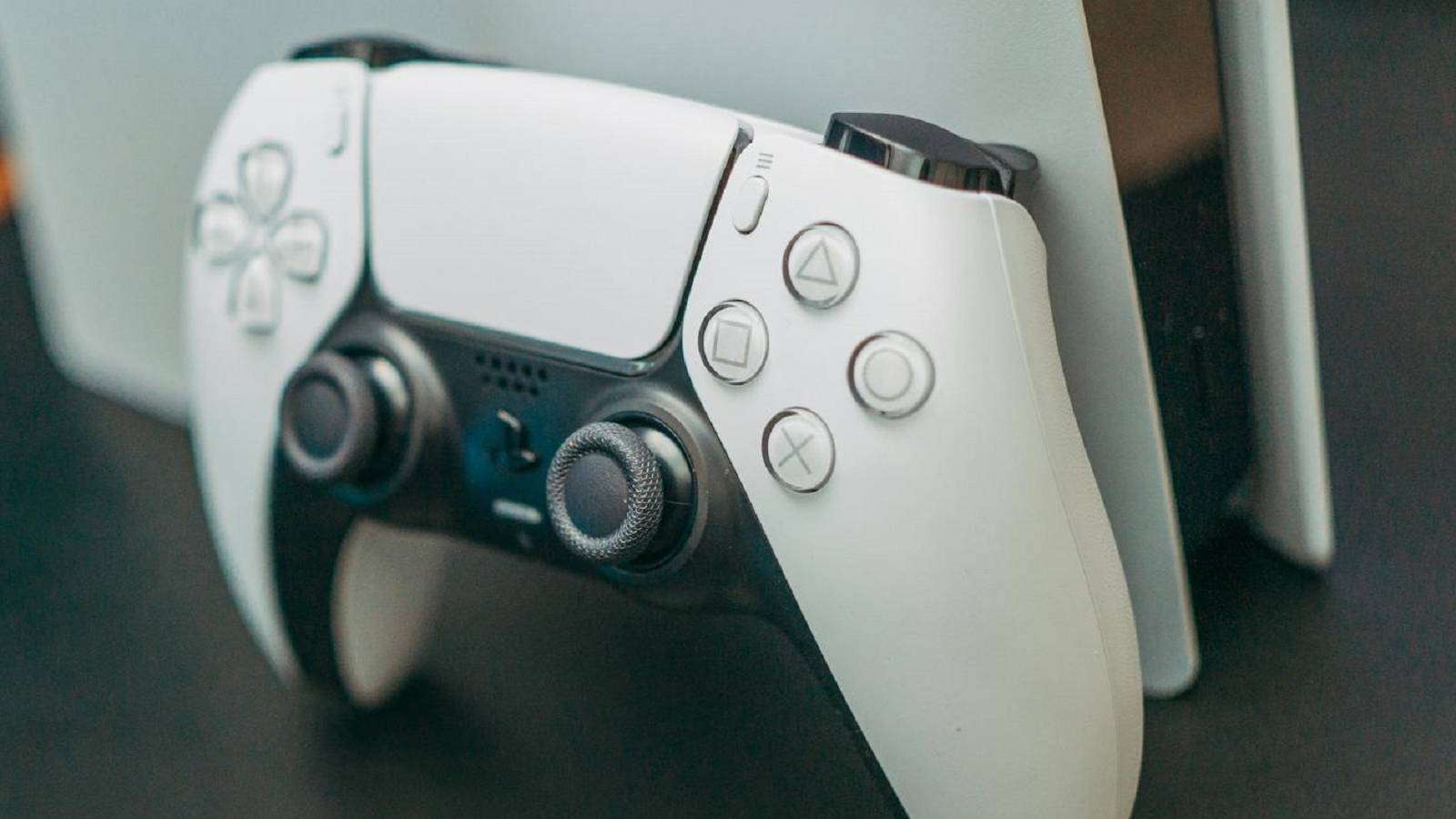 ps5 controller with console in background
