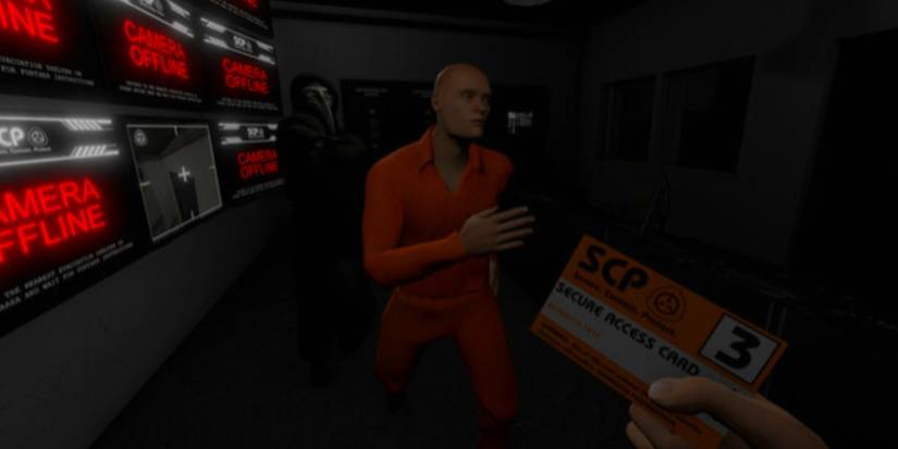 A character in an orange jumpsuit in a dark location with screens on his left side.