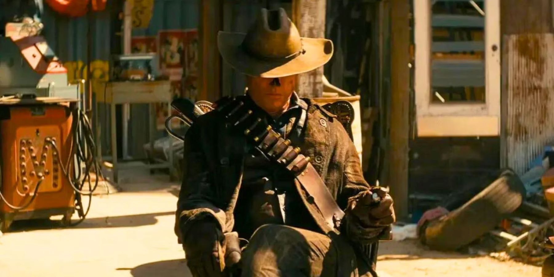 fallout tv show still of walton goggins' ghoul pointing a gun while seated