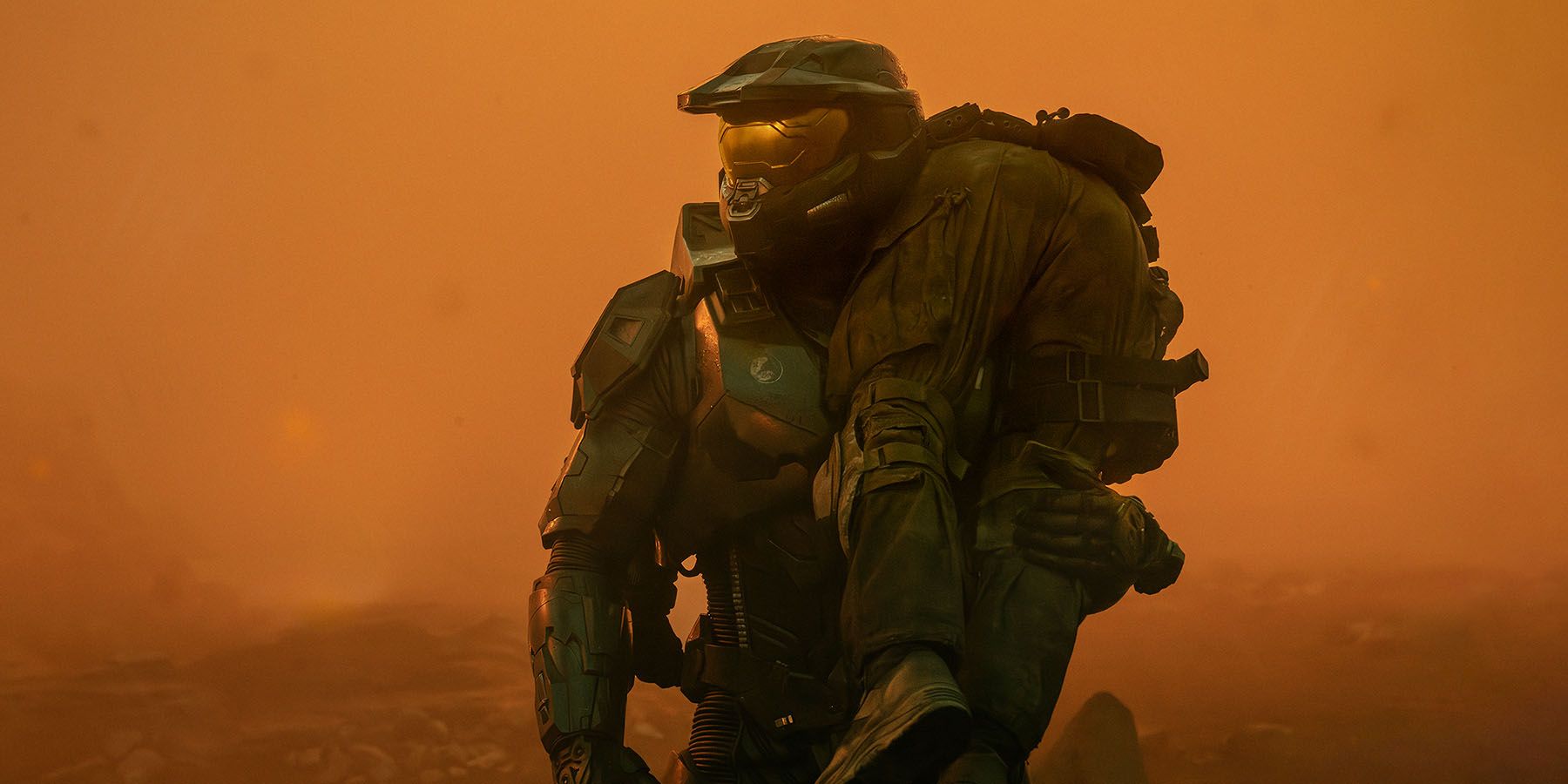A screenshot of Master Chief carrying a person over his shoulder amid a foggy orange enviroment in the Halo series.