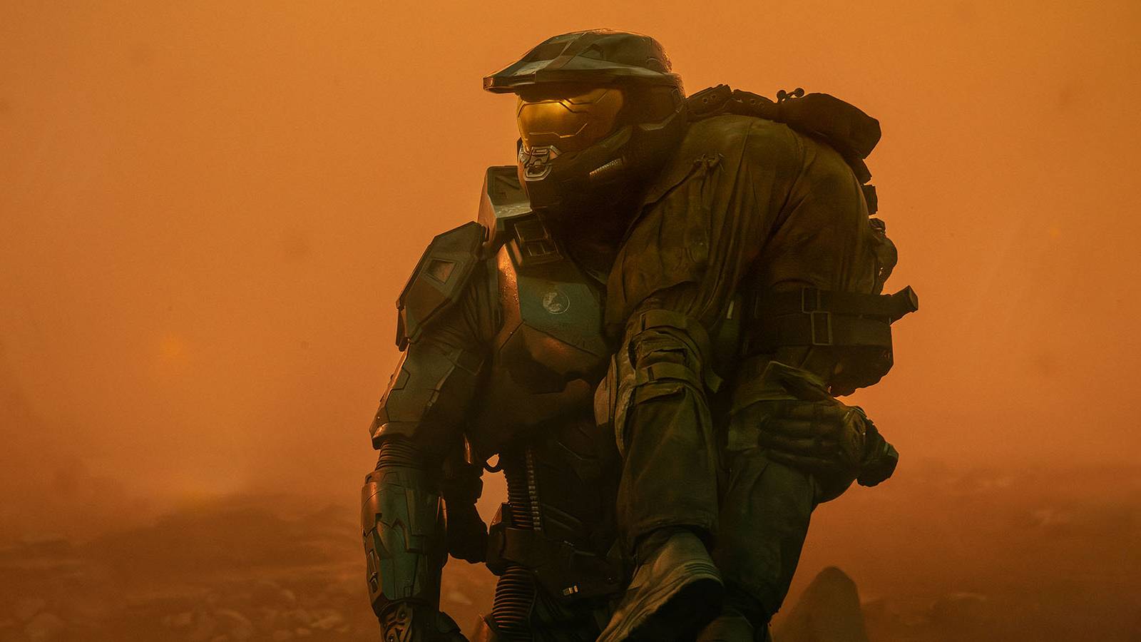 A screenshot of Master Chief carrying a person over his shoulder amid a foggy orange enviroment in the Halo series.