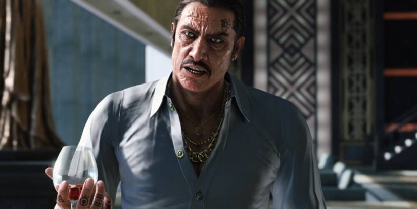 Dwight Mendez holding a glass of alcohol with a stern look on his face