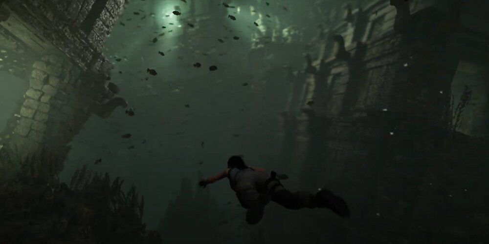 Lara Croft swimming underwater with fish all around her 