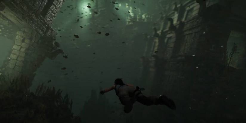 Lara Croft swimming underwater with fish all around her in Shadow of the Tomb Raider