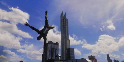 Spider-Man in a black suit doing a handstand with the Avenger's Tower in the background