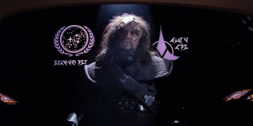 A Klingon sits in front of the Federation flag in Star Trek's "Heart of Glory".