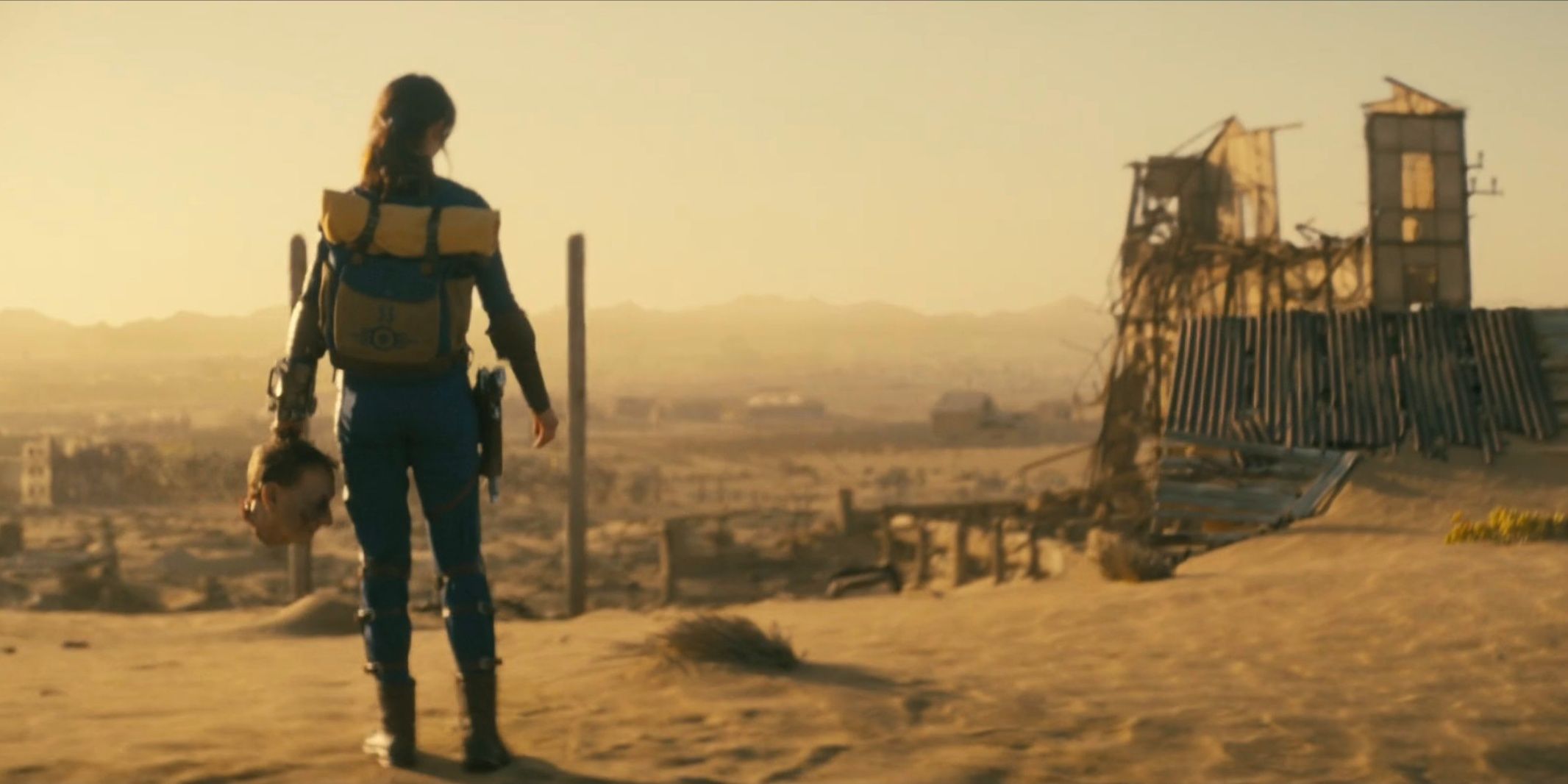 Lucy carrying a head looking out on wasteland in Fallout