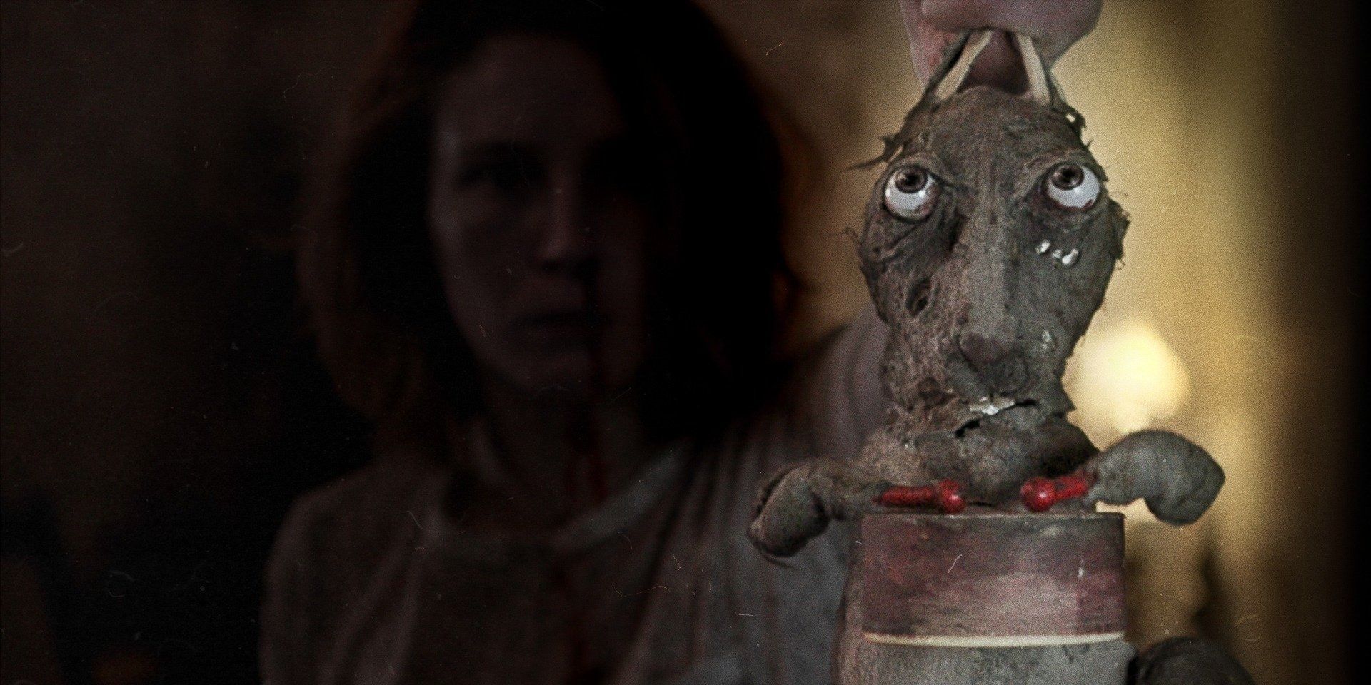 Caveat horror film still, woman holding mechanical rabbit