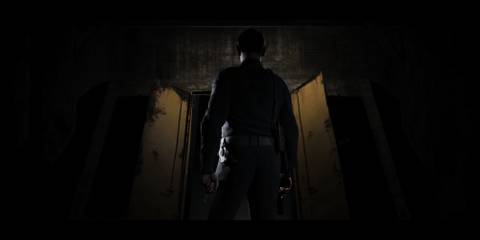 A man readies his gun as he walks into a dark room