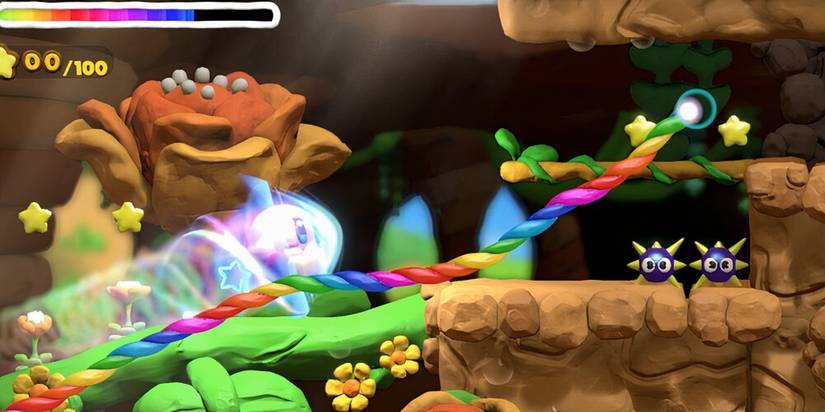 Kirby running along a multicoloured path with a flower in the background and spiked enemies 