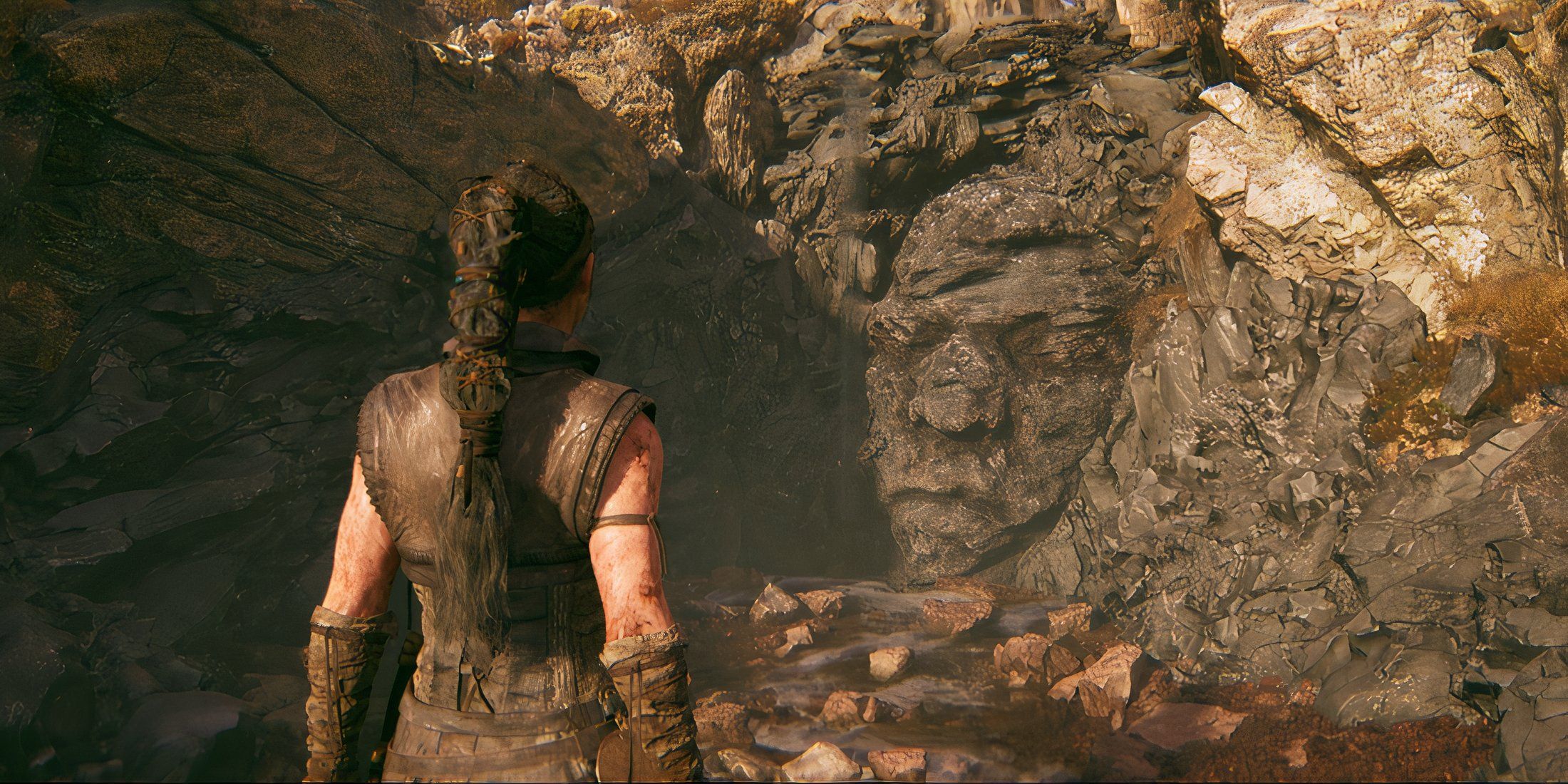 Senua standing in front of a stone face in Hellblade 2