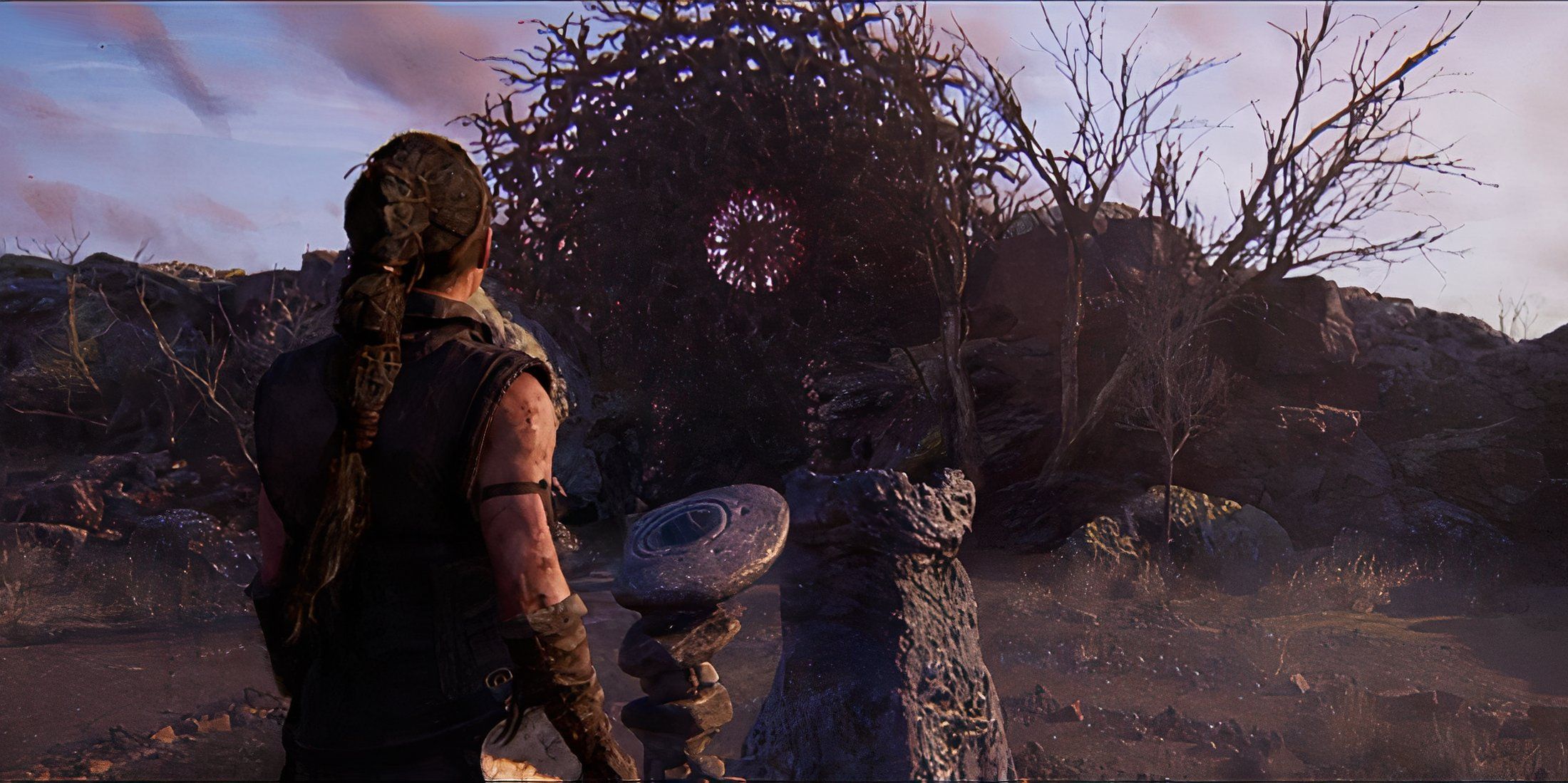 Senua standing by a stone pedestal in Hellblade 2