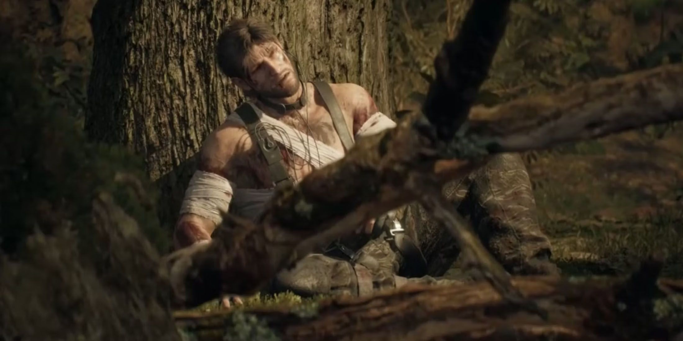 A screenshot of an injured Snake leaning against a tree in Metal Gear Solid Delta: Snake Eater.