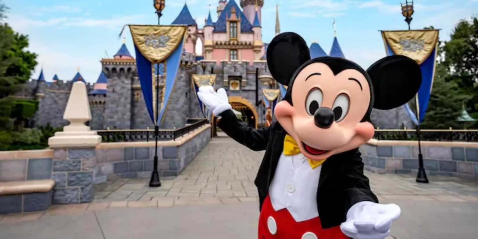 Mickey Mouse stands in front of the Sleeping Beauty Castle at Disneyland in California.