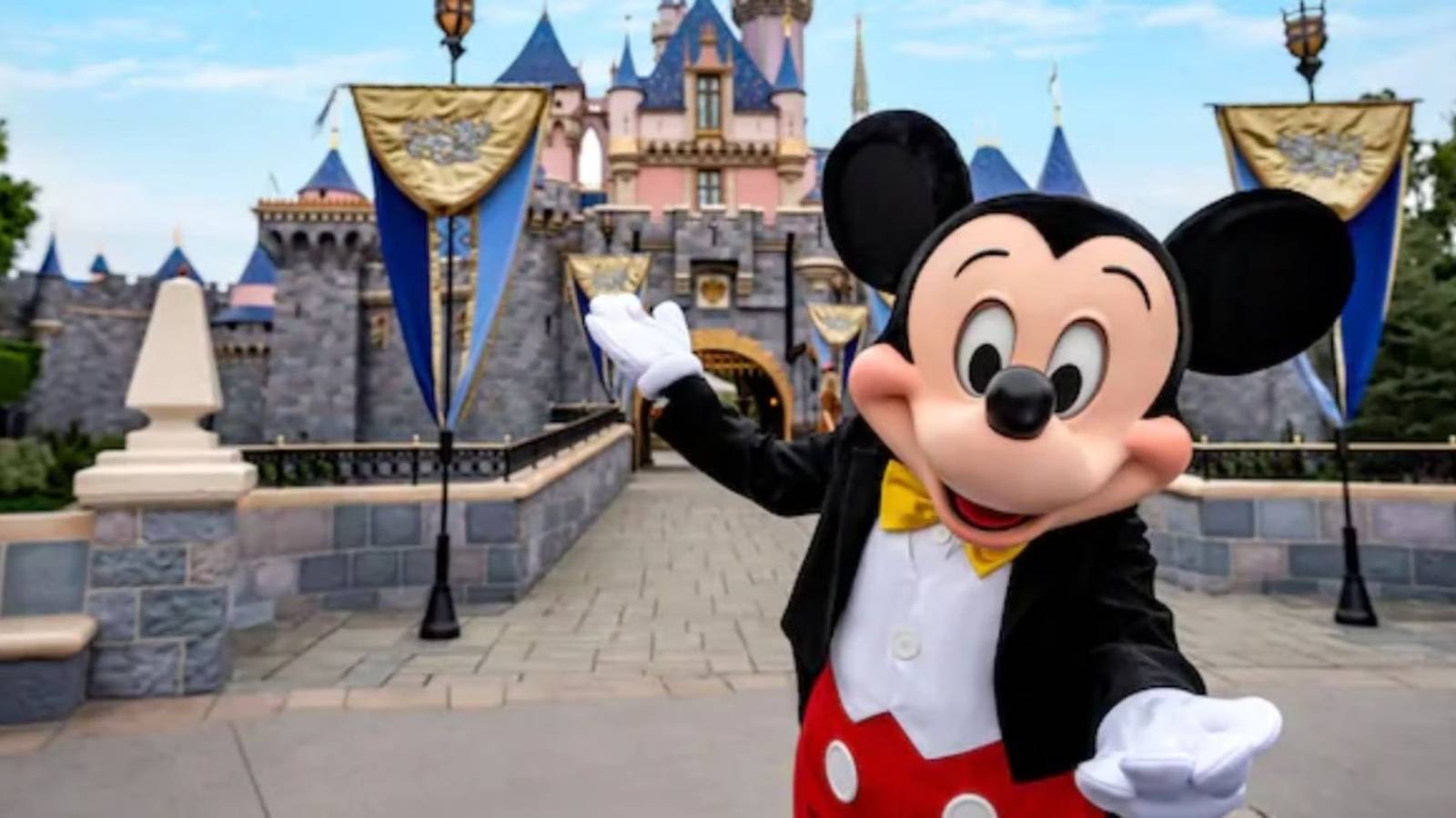 Mickey Mouse stands in front of the Sleeping Beauty Castle at Disneyland in California.