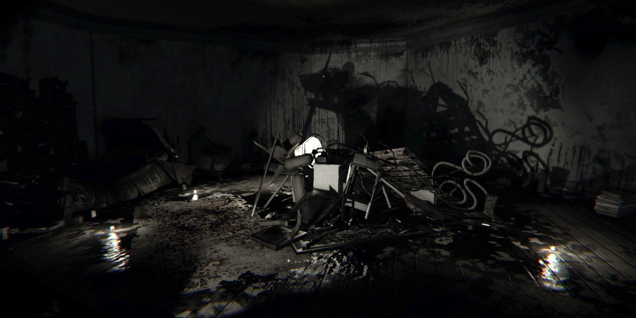 A pile of furniture in a dark room with a silhouette of a rat on the wall in Layers of Fear