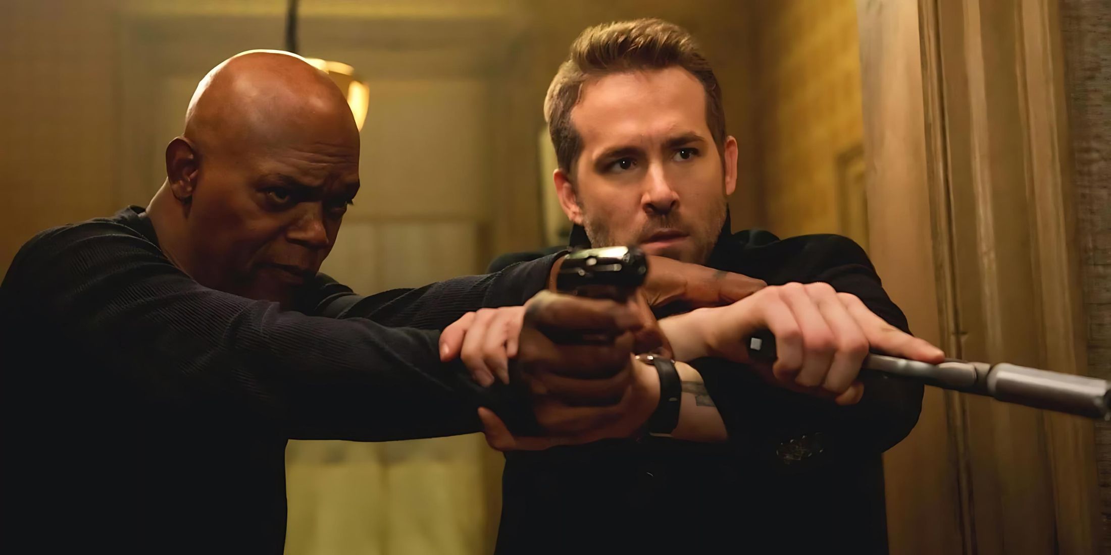 Ryan Reynolds holds a gun next to Samuel L. Jackson in “Killer's Bodyguard”