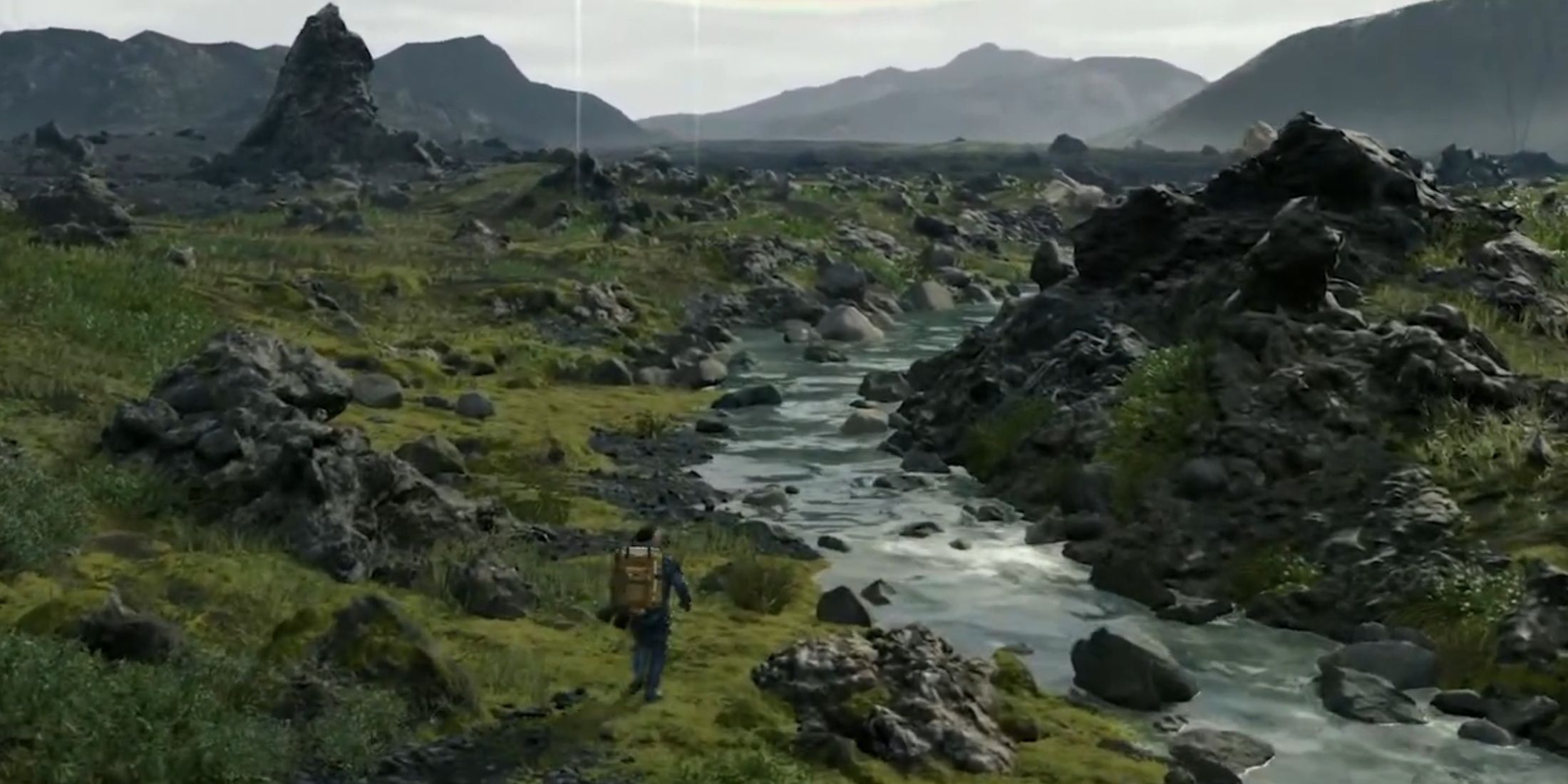 Sam Porter Bridges walks towards a river filled with rocks