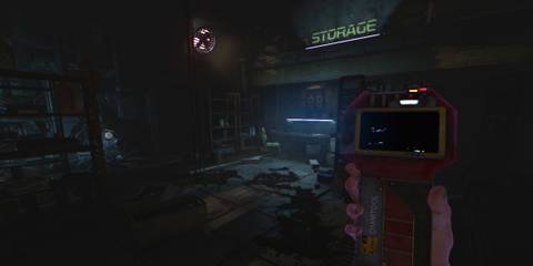 The player holding an Omnitool in a storage facility in Soma