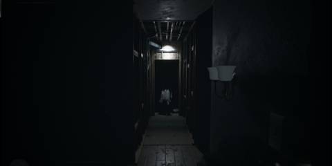 A long, dark corridor with a figure emerging from the shadows in Visage