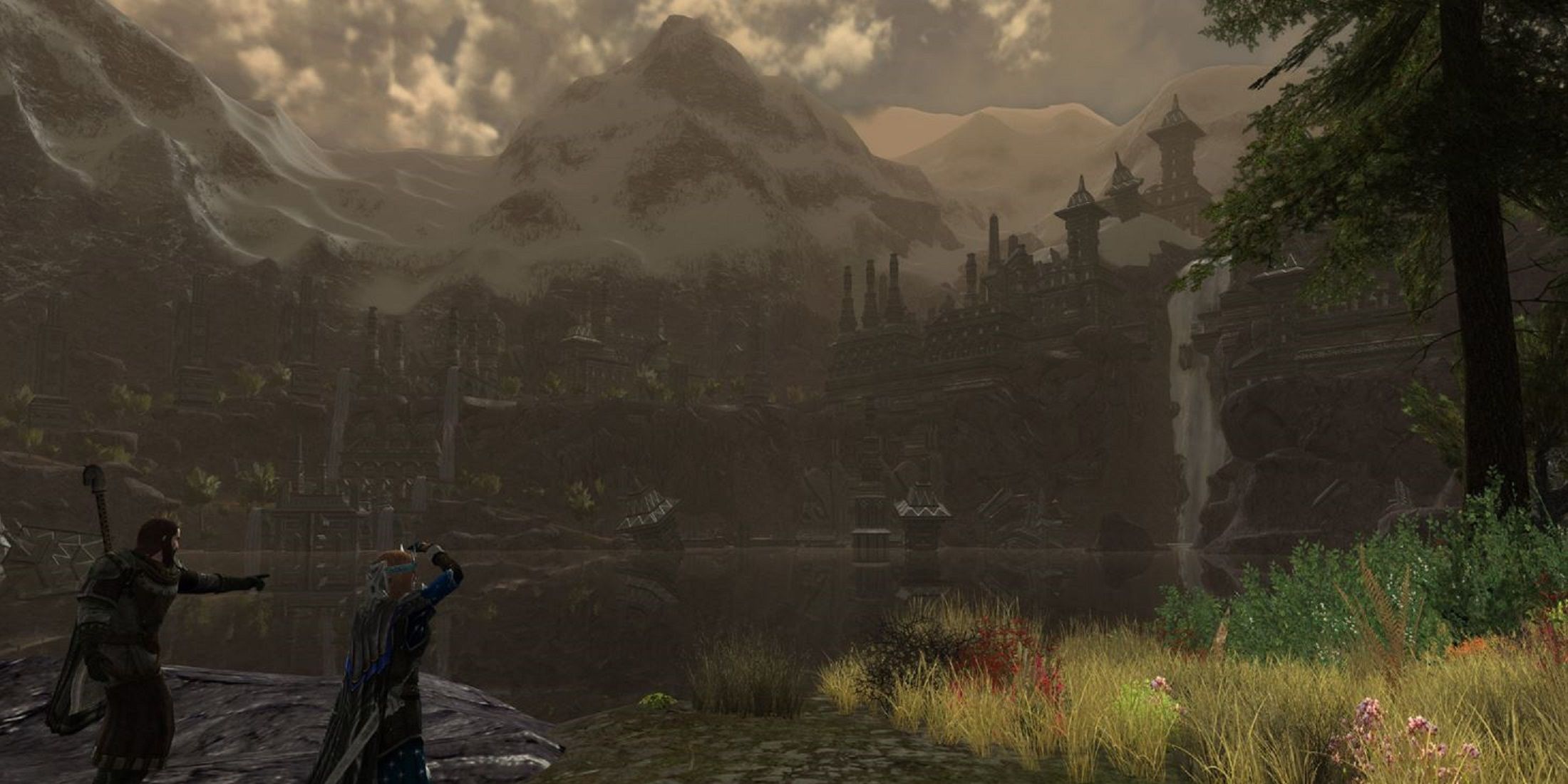 Two characters point toward a distant fortress nestled in the mountains, overlooking a misty valley in a scene from a Lord of the Rings game.