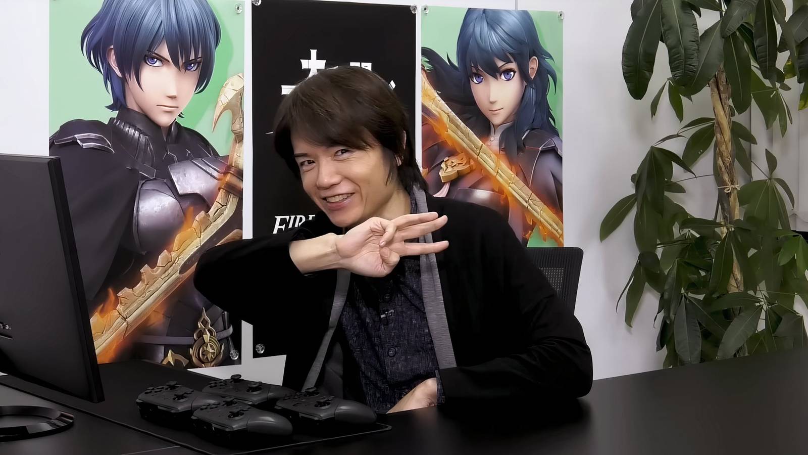 masahiro sakurai in front of byleth posters super smash bros ultimate
