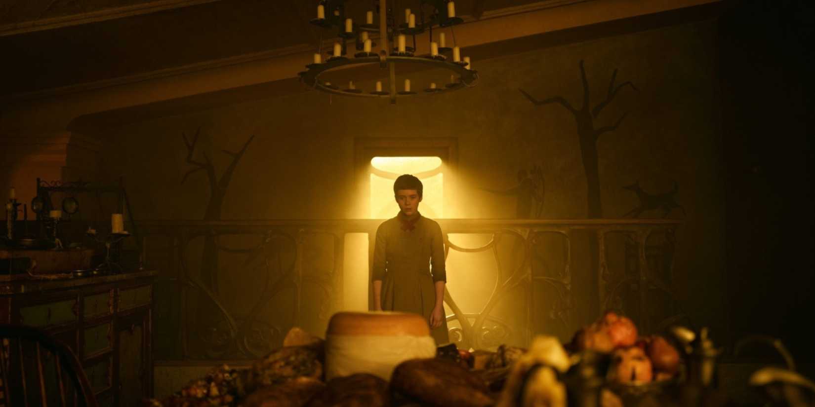 A young girl stands with her back to a sunlit window 