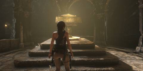 Lara Croft standing inside a tomb looking at a manuscript on a pedestal 
