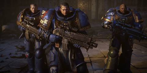 Three Space Marine 2 Ultramarines stand holding weapons.