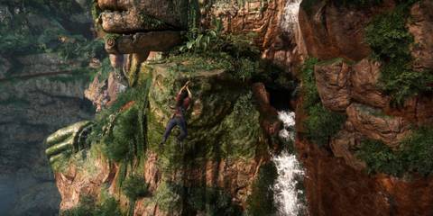 Chloe Frazer hanging from a rope in front of a cliff in Uncharted