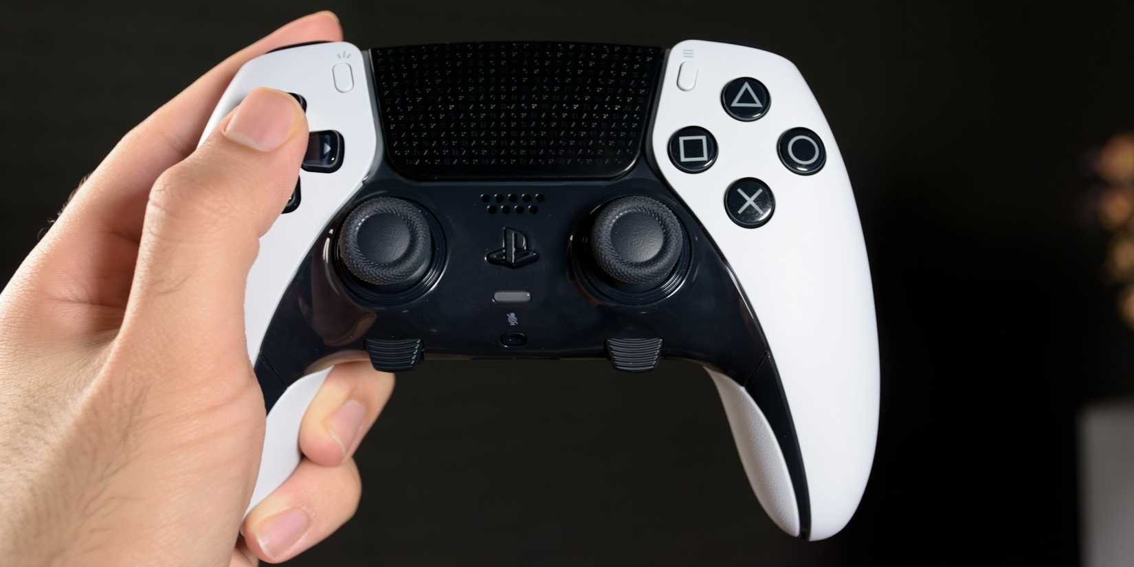 Someone holding the DualSense Edge on a black background