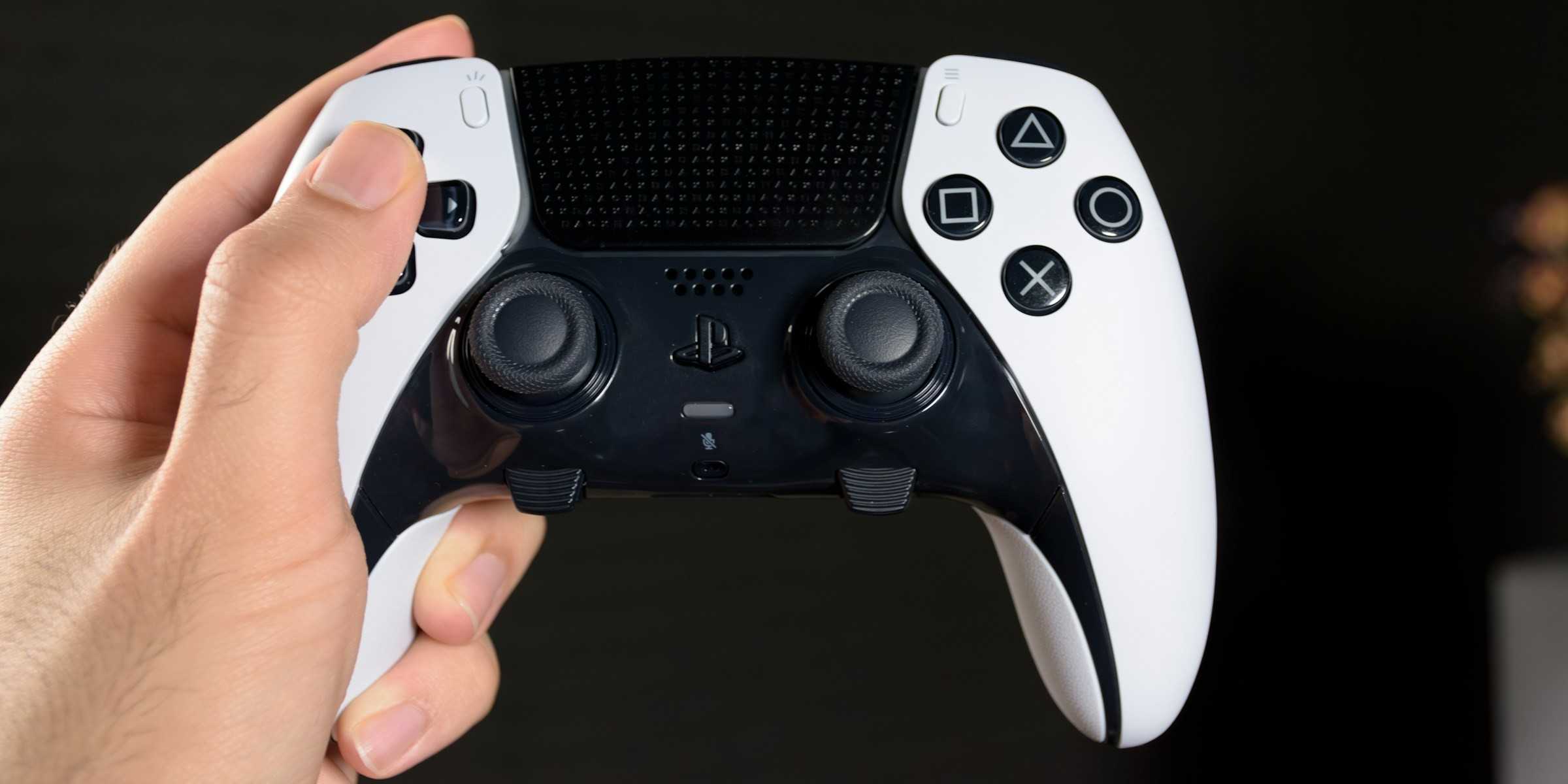 Someone holding the DualSense Edge on a black background