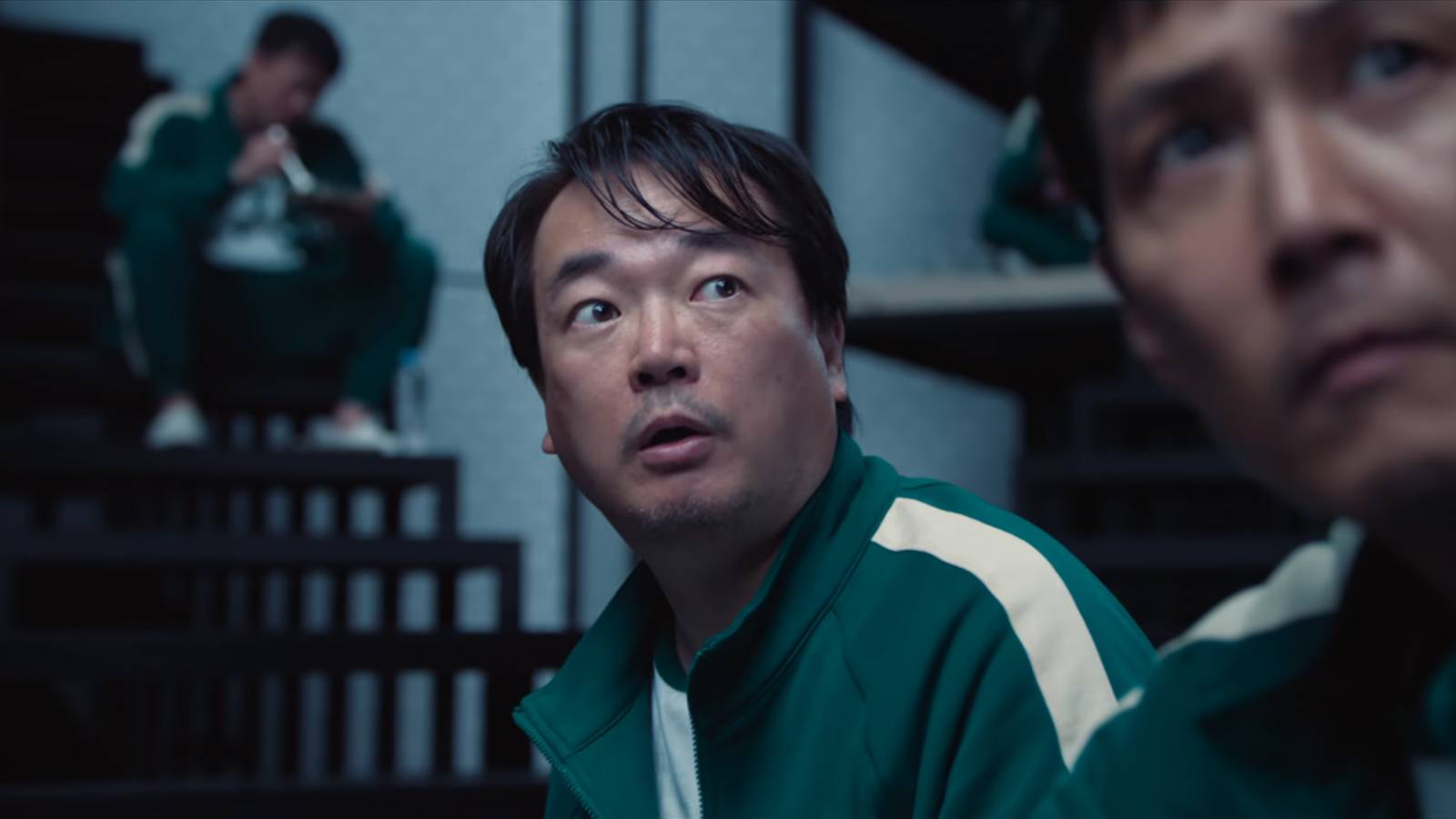 Jung-bae sits with Gi-hun at the bunks in Squid Game.