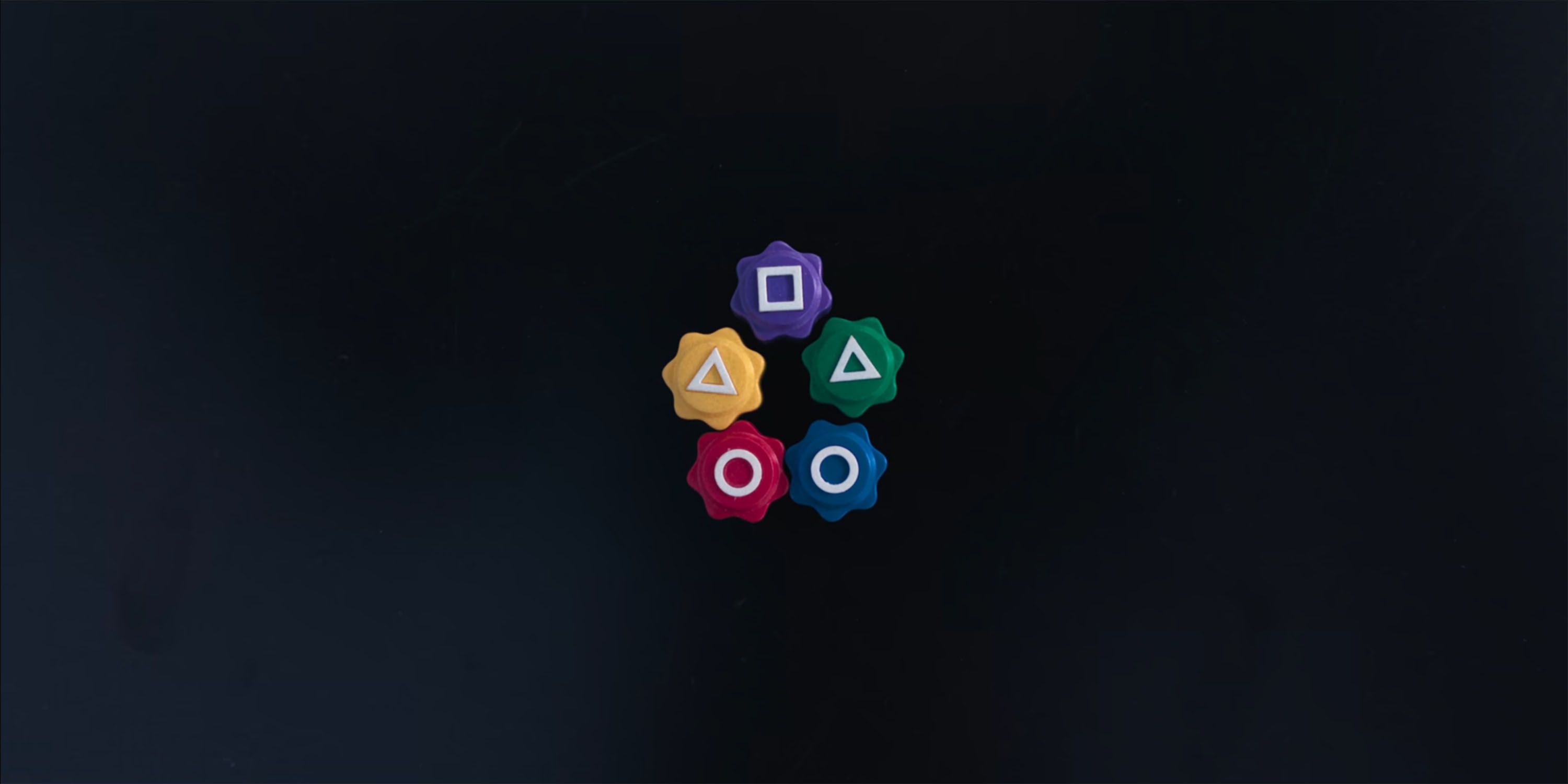 Five colorful Gonggi die sit neatly in a star shape on a black surface in Squid Game.