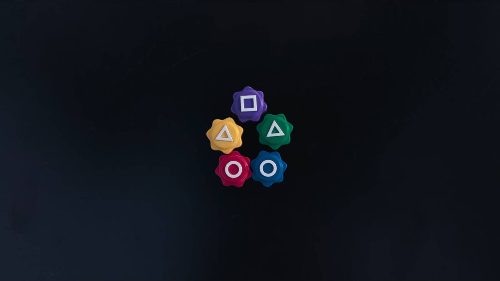 Five colorful Gonggi die sit neatly in a star shape on a black surface in Squid Game.